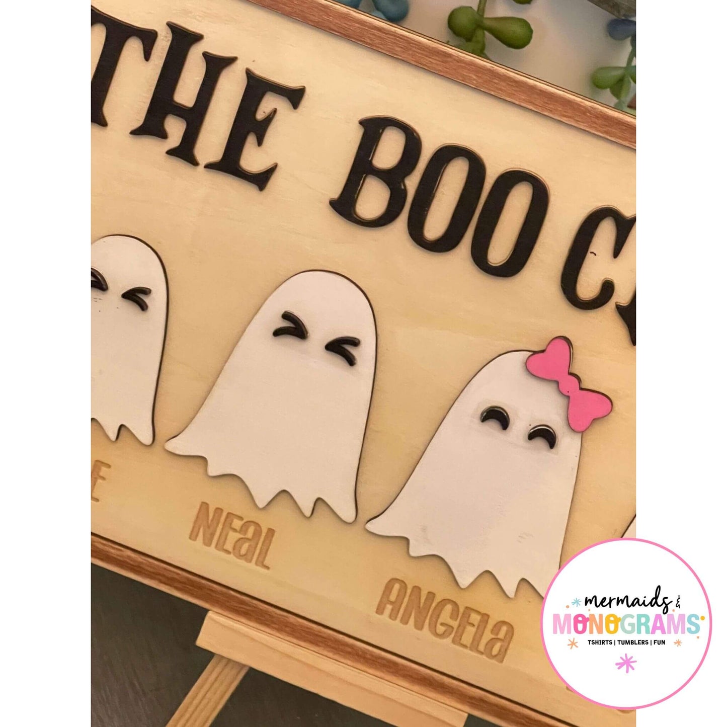 Close-up of custom laser-cut Halloween ghost characters engraved with family member names on personalized Boo Crew plaque