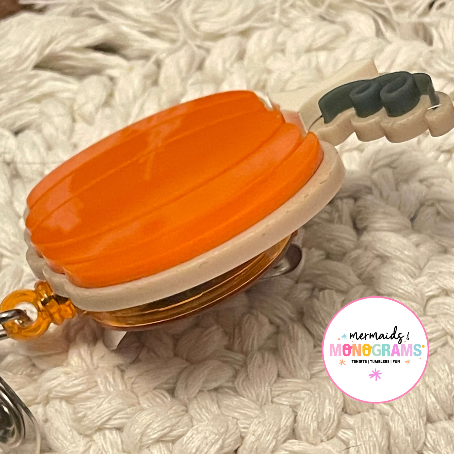 Side profile of layered pumpkin acrylic badge reel showing thickness and detail