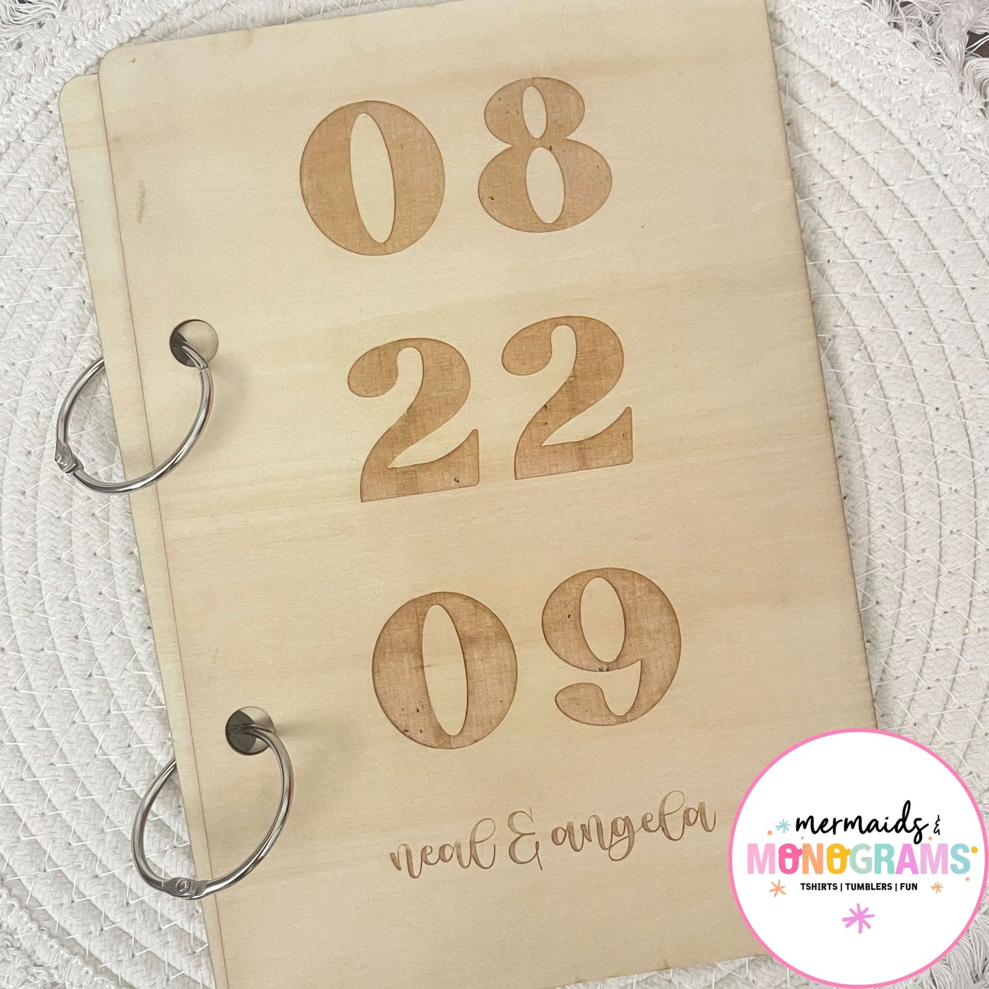 Close-up of personalized wedding card keeper with engraved date and names on natural wood