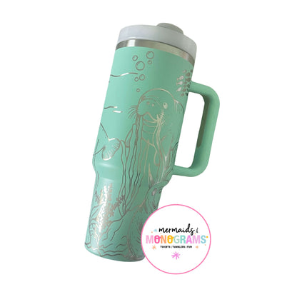 Seafoam green tumbler with silver laser-engraved manatee and coral illustrations
