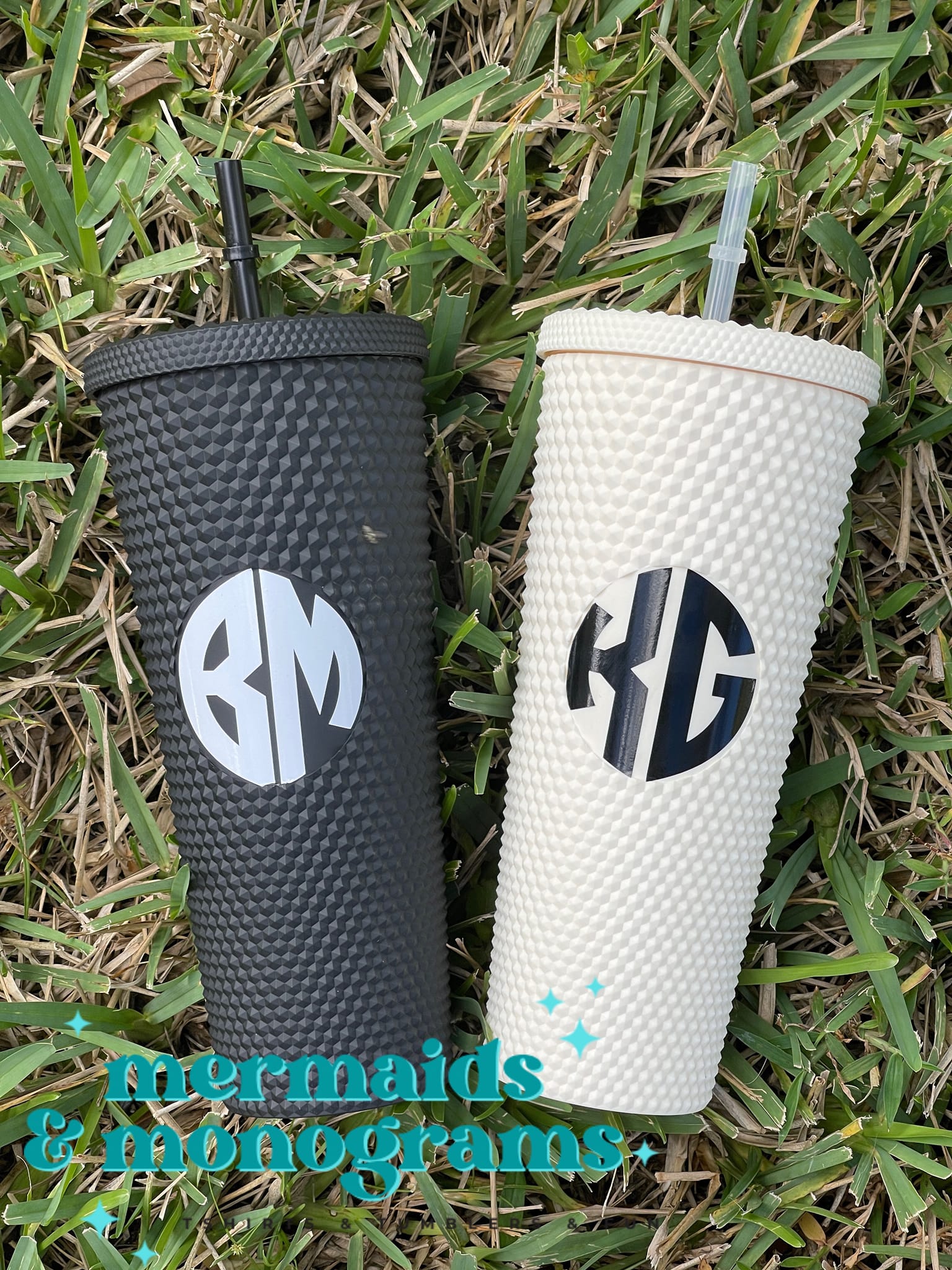 Set of black and white custom monogrammed studded tumblers resting in grass