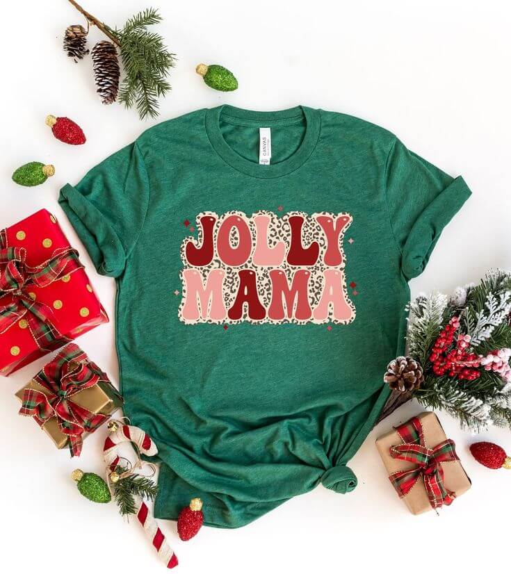 Green “Jolly Mama” Christmas shirt with leopard print and retro font styled flatlay with wrapped presents, candy canes, and pine decor.