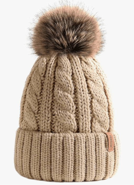 Beige knitted beanie with a brown faux fur pom-pom on a white background