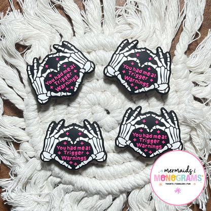 Four skeleton hand beads with text on a textured white surface, featuring the brand 'Mermaids & Monograms'.