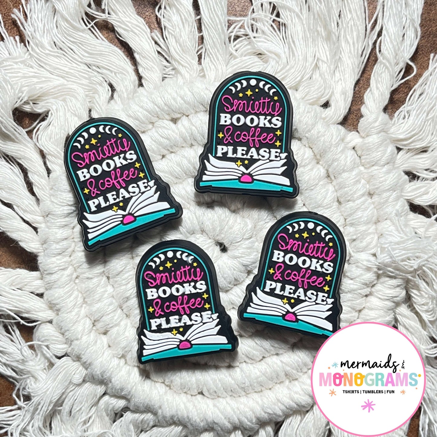 Four silicone beads with 'smuttie books & coffee, please' text on a textured white surface.
