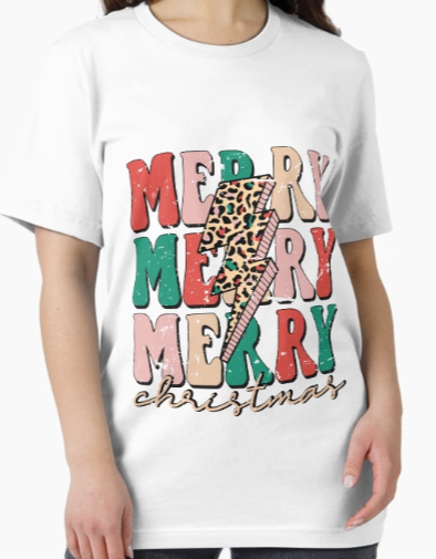 Woman wearing a white unisex t-shirt featuring “Merry Merry Merry Christmas” in colorful retro text with a leopard print lightning bolt – cute and cozy holiday shirt for women.