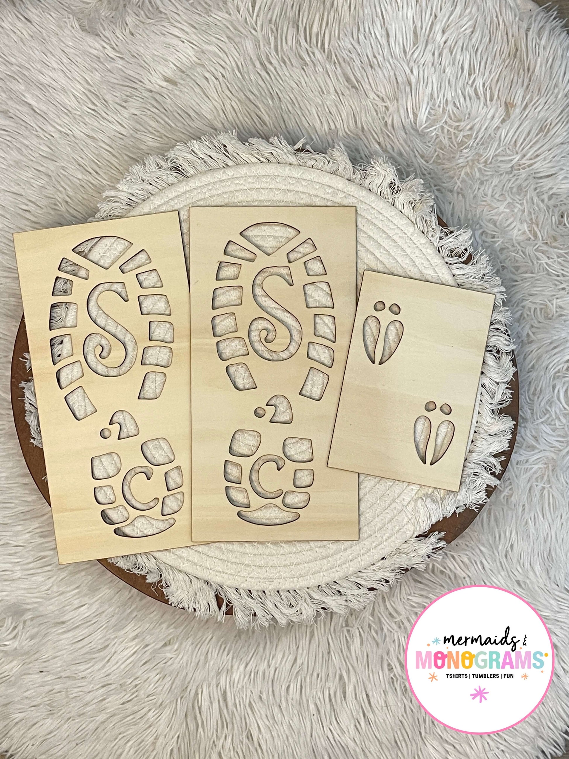 "Wooden Santa boot and reindeer footprint stencils displayed on white textured fabric – perfect for creating magical Christmas morning trails."